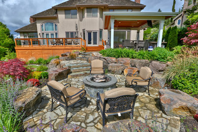 Example of a large minimalist backyard stone patio kitchen design in Seattle with a gazebo