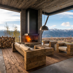 Example of a huge mountain style backyard concrete patio design in Other with a fire pit and a roof extension