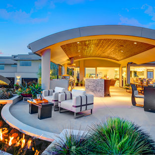 Idee per un ampio patio o portico moderno dietro casa con un tetto a sbalzo, un focolare e pavimentazioni in cemento