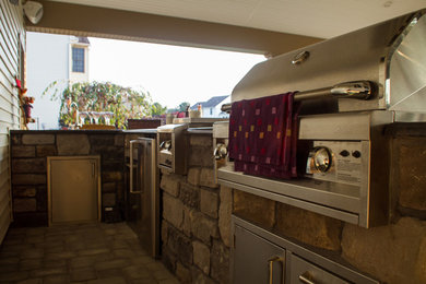 Modelo de patio tradicional grande en patio trasero y anexo de casas con cocina exterior y adoquines de hormigón