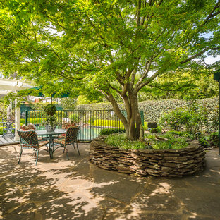 Ispirazione per un patio o portico american style di medie dimensioni e dietro casa con pavimentazioni in pietra naturale e un parasole