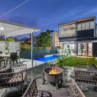 Design ideas for a contemporary backyard patio in Brisbane with a fire feature.