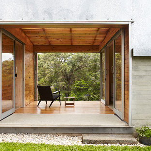 Idee per un piccolo patio o portico industriale dietro casa con pedane e un tetto a sbalzo
