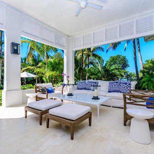 Idee per un grande patio o portico tropicale dietro casa con piastrelle e un tetto a sbalzo