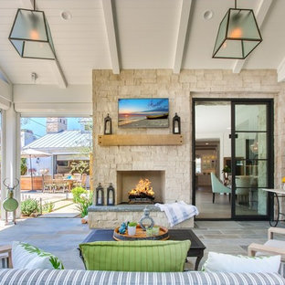 Foto di un grande patio o portico country dietro casa con un focolare, pavimentazioni in pietra naturale e un tetto a sbalzo