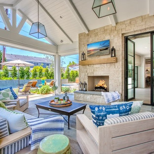 Idee per un grande patio o portico country dietro casa con un focolare, pavimentazioni in pietra naturale e un tetto a sbalzo