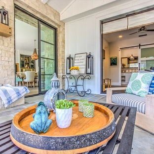 Foto di un grande patio o portico country dietro casa con un focolare, pavimentazioni in pietra naturale e un tetto a sbalzo