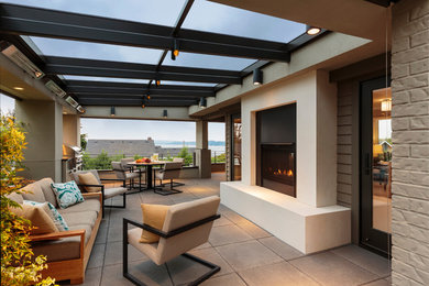 Large minimalist backyard concrete paver patio photo in Seattle with a fire pit and a roof extension