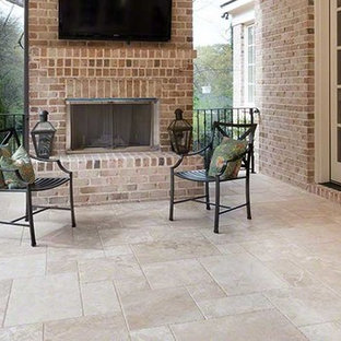 Idee per un patio o portico stile americano di medie dimensioni e dietro casa con un focolare, piastrelle e un tetto a sbalzo