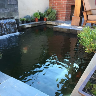Ispirazione per un patio o portico etnico di medie dimensioni e dietro casa con fontane, piastrelle e una pergola