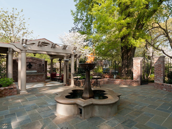 Picture of a sizable stone patio in a courtyard with a fire pit and a pergola