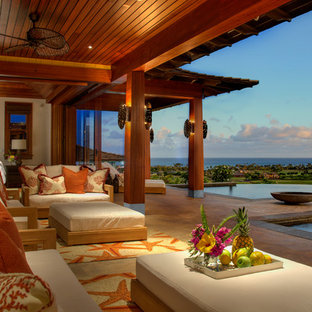 Immagine di un ampio patio o portico tropicale dietro casa con un focolare, piastrelle e un tetto a sbalzo
