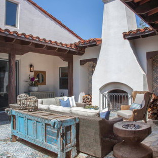 Ispirazione per un patio o portico mediterraneo con un caminetto, piastrelle e nessuna copertura