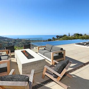Patio - huge contemporary backyard concrete paver patio idea in Orange County with a fireplace and no cover