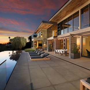 Inspiration for a huge contemporary backyard concrete paver patio remodel in Orange County with a fireplace and no cover