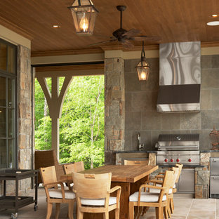 Idee per un grande patio o portico chic dietro casa con pavimentazioni in pietra naturale e un tetto a sbalzo