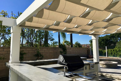 Example of a mid-sized trendy backyard patio kitchen design in Orange County with a pergola