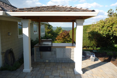 Modelo de patio de estilo americano grande en patio trasero con cocina exterior, adoquines de ladrillo y pérgola