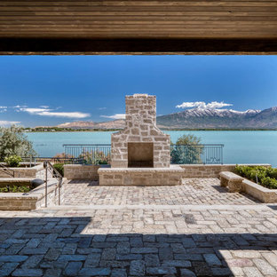Idee per un ampio patio o portico vittoriano in cortile con un caminetto, pavimentazioni in pietra naturale e un tetto a sbalzo
