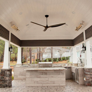 Immagine di un patio o portico stile rurale di medie dimensioni e dietro casa con un focolare, un tetto a sbalzo e cemento stampato