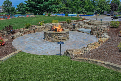 Example of a large classic backyard stone patio design in Chicago with a fire pit and no cover