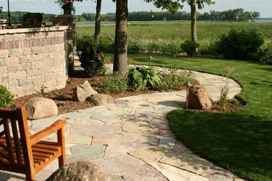 Large mountain style backyard stone patio photo in Other