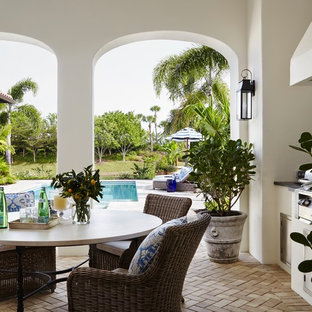 Ispirazione per un grande patio o portico tropicale dietro casa con pavimentazioni in mattoni e un tetto a sbalzo