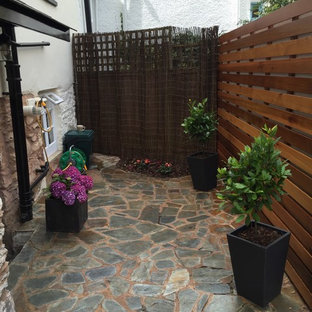 Idee per un piccolo patio o portico moderno in cortile con pavimentazioni in pietra naturale e nessuna copertura