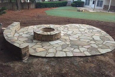 This is an example of a medium sized traditional back patio in Atlanta with a fire feature, natural stone paving and no cover.