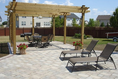 Example of a large backyard concrete paver patio design in Other with a pergola