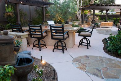 Imagen de patio actual de tamaño medio en patio trasero con cocina exterior, adoquines de piedra natural y pérgola
