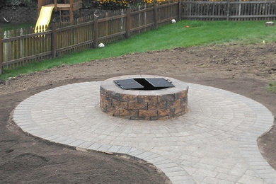 Example of a large minimalist backyard stone patio design in New York with a fire pit and no cover