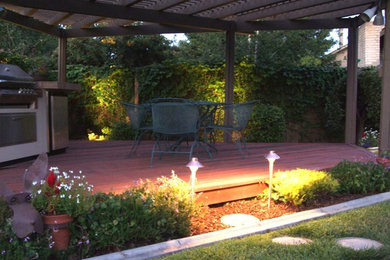 Modelo de patio contemporáneo de tamaño medio en patio trasero con cocina exterior, entablado y pérgola