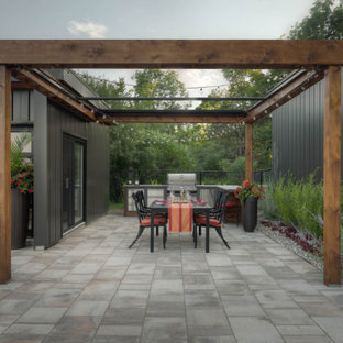 Imagen de patio minimalista, grande, en patio trasero, con cocina exterior, adoquines de piedra natural y pérgola