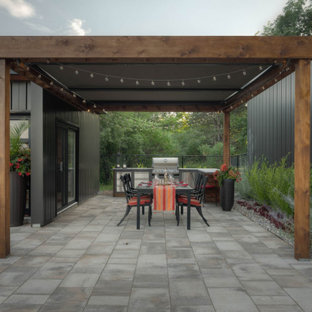 Ejemplo de patio minimalista, grande, en patio trasero, con cocina exterior, adoquines de piedra natural y toldo