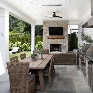Esempio di un patio o portico country di medie dimensioni e dietro casa con pavimentazioni in pietra naturale e un tetto a sbalzo