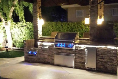 Small modern back patio in Las Vegas with an outdoor kitchen, concrete slabs and a gazebo.