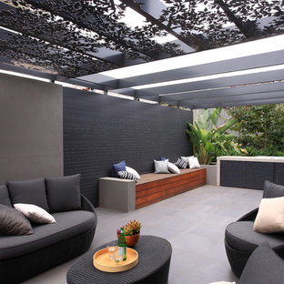 Immagine di un patio o portico minimalista di medie dimensioni e nel cortile laterale con piastrelle e una pergola