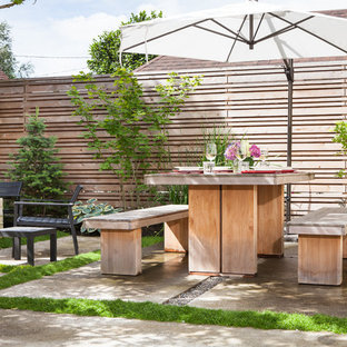Esempio di un piccolo patio o portico moderno dietro casa con pavimentazioni in cemento e un parasole