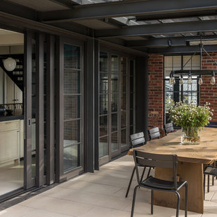 Ispirazione per un grande patio o portico chic dietro casa con un focolare, pavimentazioni in cemento e una pergola