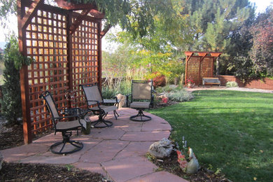 Example of an arts and crafts backyard stone patio design in Denver
