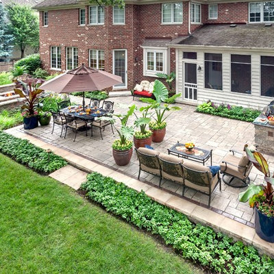 Example of a large classic backyard brick patio design in Chicago with a fire pit and no cover
