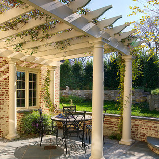 Idee per un grande patio o portico chic in cortile con pavimentazioni in pietra naturale e una pergola