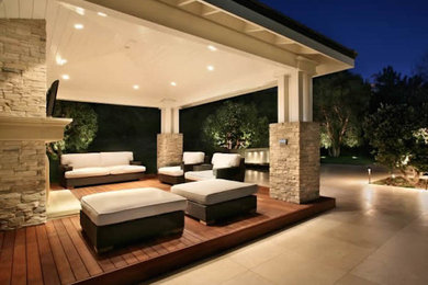 Example of a mid-sized transitional backyard patio design in Phoenix with a fire pit, decking and a roof extension