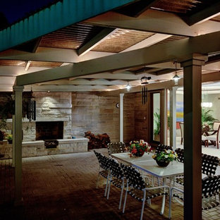 Idee per un patio o portico etnico di medie dimensioni e dietro casa con un focolare, pavimentazioni in mattoni e un tetto a sbalzo