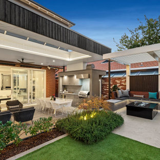 This is an example of a large contemporary backyard patio in Melbourne with an outdoor kitchen, concrete pavers and a roof extension.