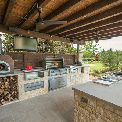 Large elegant backyard stone patio kitchen photo in Dallas with a roof extension