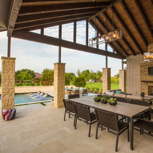 Esempio di un grande patio o portico tradizionale dietro casa con pavimentazioni in pietra naturale, un tetto a sbalzo e un caminetto