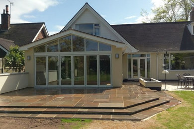 Design ideas for a large modern back patio in Cheshire with natural stone paving.