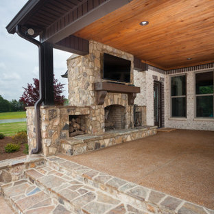 Immagine di un grande patio o portico tradizionale dietro casa con un caminetto, graniglia di granito e un tetto a sbalzo